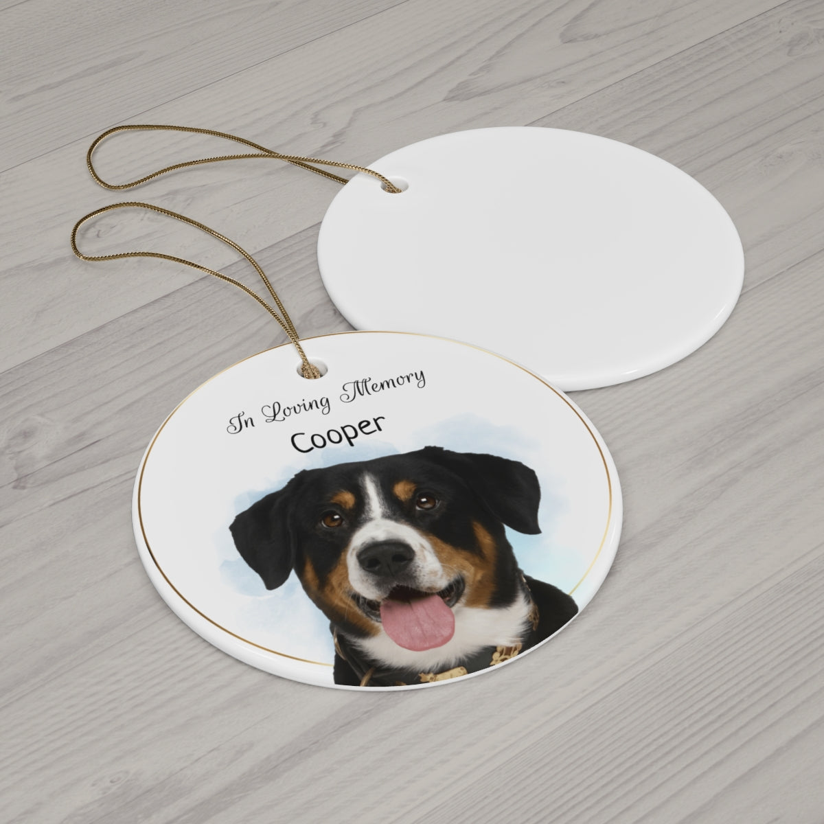 Round ceramic ornament with a dog's face and 'In Loving Memory Cooper' text on a wooden surface.