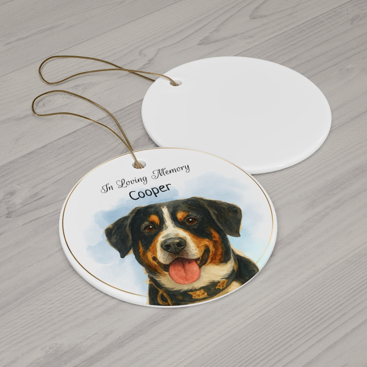 Round ceramic ornament with a dog's face and 'In Loving Memory Cooper' text on a wooden surface.